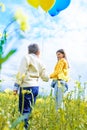 Vertical portrait happy two children run on a yellow field, blooming rapeseed. blue sky and clouds. Blue and yellow Royalty Free Stock Photo