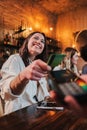 Vertical portrait of happy young woman paying bill with a contactless credit card in a restaurant. Cheerful female Royalty Free Stock Photo