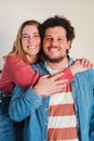 Vertical portrait of heterosexual young caucasian couple embracing together at home living room, looking at camera with Royalty Free Stock Photo