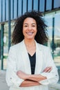 Vertical portrait of a hispanic arms crossed business woman with curly hair smiling looking at camera and standing at Royalty Free Stock Photo