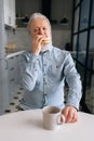 Vertical portrait of hungry mature elderly male eating fast food enjoying dinner at home and drink coffee. Hungry senior