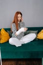 Vertical portrait of injured young woman with broken arm wrapped in white gypsum bandage talking on smartphone sitting
