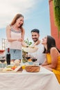 Vertical portrait of a joyful woman gathered with her friends, serving a lunch sitting at table talking and drinking Royalty Free Stock Photo