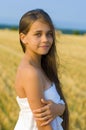 Vertical portrait of a long-haired green-eyed teenager girl against the sky and a mown wheat field