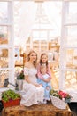 Vertical portrait of loving blonde young mother in dress sitting on doorstep of summer gazebo house with two little Royalty Free Stock Photo