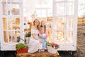 Vertical portrait of loving blonde young mother in dress sitting on doorstep of summer gazebo house with two little Royalty Free Stock Photo