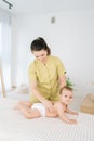 Vertical portrait of loving mother massaging little baby. Front view of adorable infant baby boy lying on belly while Royalty Free Stock Photo