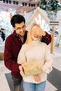 Vertical portrait of loving young man covering eyes happy smiling girlfriends standing in hall of celebrate shopping Royalty Free Stock Photo