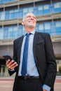 Vertical portrait of a mature business man in a blazer, tie and dress shirt, standing in front of a building, is smiling Royalty Free Stock Photo