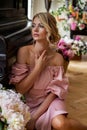 Vertical portrait of a pensive blonde with peonies