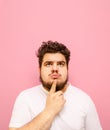 Vertical portrait of pensive young man with beard and overweight on pink background,looking up at copy space and thinking.Pensive Royalty Free Stock Photo