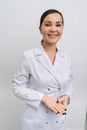 Vertical portrait of positive young woman doctor wearing coat uniform standing on isolated white background. Studio Royalty Free Stock Photo