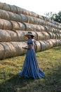 Vertical portrait of a pretty brunette with a book on the background of haystacks