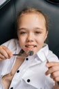 Vertical portrait of pretty little child girl holding dentistry mirror and tool lying on dental chair in stomatologist Royalty Free Stock Photo