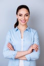 Vertical portrait of pretty young manager in formalwear stnding with crossed arms against gray background Royalty Free Stock Photo