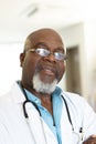 Vertical portrait of senior african american male doctor in hospital corridor, with copy space Royalty Free Stock Photo