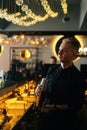 Vertical portrait of serious barman mixing ingredients of fresh cocktail by shaking shaker standing behind bar counter. Royalty Free Stock Photo