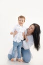 Vertical portrait of single mother, dark haired woman caring and holding little boy on floor, son, embracing on weekend Royalty Free Stock Photo