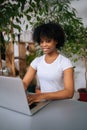 Vertical portrait of smiling African-American female freelancer working on laptop computer sitting at desk at home Royalty Free Stock Photo