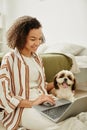 Smiling black girl using laptop on floor with little pet dog Royalty Free Stock Photo