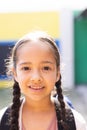 Vertical portrait of smiling cauasian elementary schoolgirl in school playground, copy space