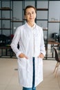 Vertical portrait of smiling female doctor wearing white medical uniform standing in hospital office, looking at camera. Royalty Free Stock Photo