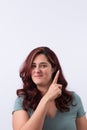 Vertical portrait of a smiling, pretty woman pointing her finger upwards. Light background and copy space. Royalty Free Stock Photo