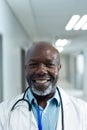 Vertical portrait of smiling senior african american male doctor in hospital corridor, copy space Royalty Free Stock Photo