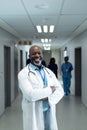 Vertical portrait of smiling senior african american male doctor in hospital corridor, copy space Royalty Free Stock Photo