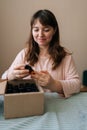 Vertical portrait of smiling young craftswoman choosing scented perfume for creating candle building mixture. Process of