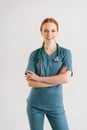 Vertical portrait of smiling young female doctor in medical uniform wearing stethoscope around neck, with arms crossed Royalty Free Stock Photo