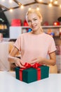 Vertical portrait of smiling young woman wrapping Christmas gift box tying red ribbon and decorating beautiful bow Royalty Free Stock Photo