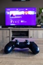 A vertical portrait of a sony playstation 4 controller in front of a television with the playstation home menu displayed on it. Royalty Free Stock Photo