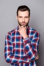 A vertical portrait of stylish bearded handsome guy touching his chin and posing against gray background Royalty Free Stock Photo