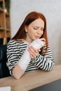 Vertical portrait of suffering from pain crying young woman with broken right hand wrapped in gypsum bandage sitting at