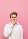 Vertical portrait of surprised young man in casual clothes isolated on pink background, looks into camera with shocked face and Royalty Free Stock Photo