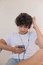 Teenager boy with messy hair using smartphone and wearing headph