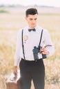 The vertical portrait of the thinkfull groom looking down and holding the binoculars and the vintage suit at the Royalty Free Stock Photo