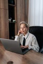 Vertical portrait of thoughtful middle-aged adult 50s woman working on laptop computer in office looking to screen Royalty Free Stock Photo