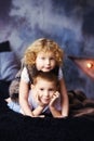 Vertical portrait of two children, boy and girl, brother and sister, siblings, laying in bed in loft styled bedroom. Curly blonde Royalty Free Stock Photo