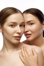 Vertical portrait of two young beautiful young Caucasian woman with clean fresh skin against white studio background