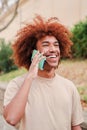 Vertical portrait of young african american guy smiling having a mobile phone call. Happy teenager with toothy smile Royalty Free Stock Photo