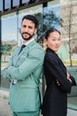 Vertical portrait of young arms crossed executive coworkers looking at camera at workplace buildings. Finance business Royalty Free Stock Photo