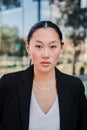Vertical portrait of young asian business woman or executive looking serious at camera wearing a suit standing at Royalty Free Stock Photo