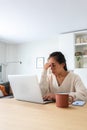 Vertical portrait of young Asian woman feeling tired and having headache after working long hours at home office. Royalty Free Stock Photo