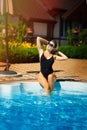 Vertical portrait of young beautiful sexy tanned slim blonde woman in sunglasses and bandage with legs in swimming pool in black Royalty Free Stock Photo