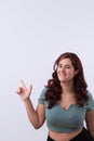 Vertical portrait of a young and beautiful woman smiling and pointing her finger upwards. Royalty Free Stock Photo