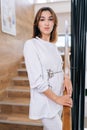 Vertical portrait of young confident female doctor or nurse in white medical gown standing posing on staircase at modern Royalty Free Stock Photo