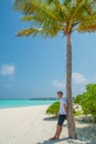 Vertical portrait of young handsome attractive man wearing t-shirt and shorts at tropical beach at island luxury resort Royalty Free Stock Photo