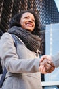 Vertical portrait of a young hispanic woman shaking hands with her partner. Business female doing a handshake with her Royalty Free Stock Photo